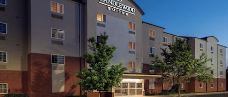 A hotel with a modern facade, a prominent signage for 'Candlewood Suites,' and a well-maintained entrance area with a clear pathway.