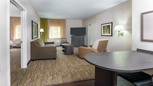 A hotel room with a sofa, armchair, small round table, and a flat-screen TV. - Candlewood Suites Athens by IHG (Athens)