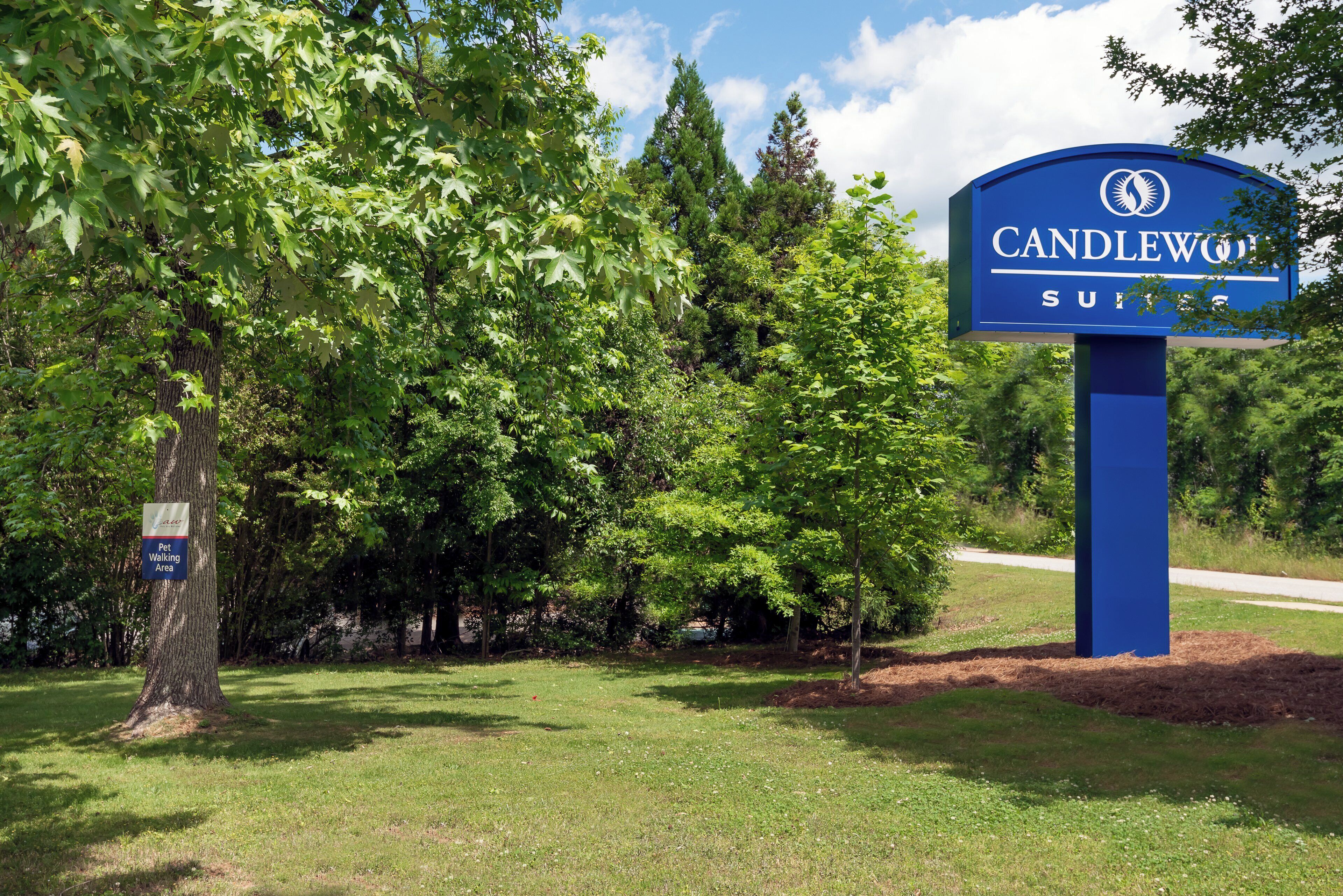 A sign for Candlewood Suites with a pet walking area nearby.