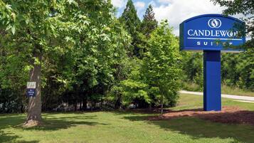 A sign for Candlewood Suites with a pet walking area nearby.