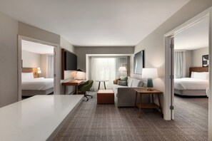 A hotel room with two beds, a desk, a chair, a sofa, and a small table. - Staybridge Suites Wichita by IHG (Wichita)