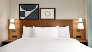 Una habitación de hotel con una cama grande, dos lámparas de noche y dos cuadros enmarcados en la pared.