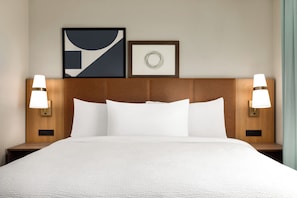 Une chambre d’hôtel avec un grand lit, deux lampes de chevet et deux œuvres d’art encadrées accrochées au mur.