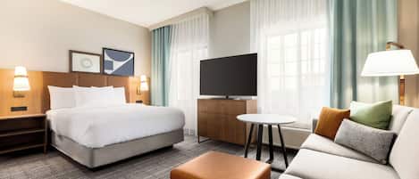 Une chambre d’hôtel équipée d’un lit, d’une télévision, d’un canapé, d’une table basse et d’un bureau.