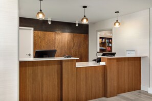 A reception desk with a wooden panel design, a computer, and a cash register. - Staybridge Suites Wichita by IHG (Wichita)