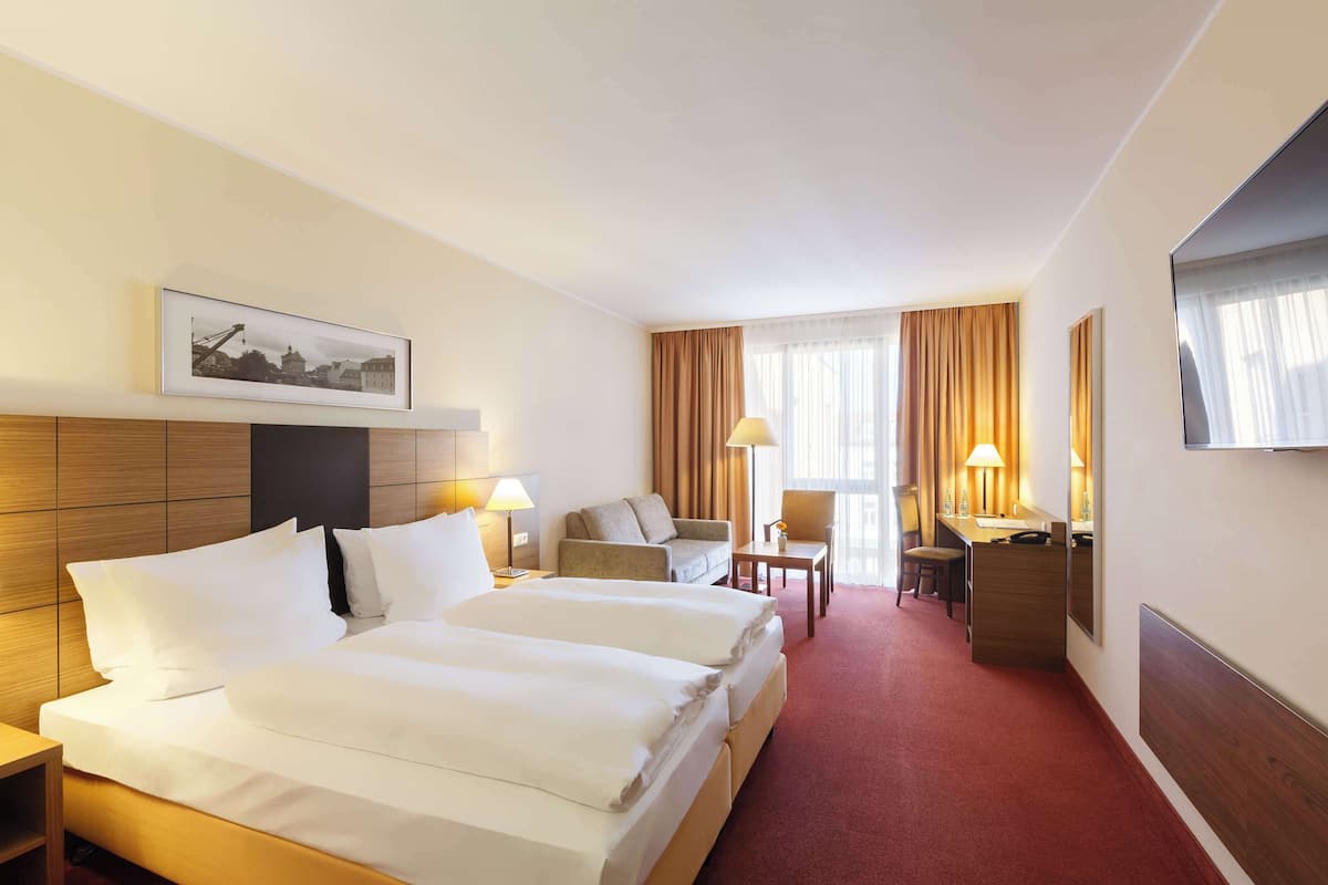 A hotel room with two beds, a desk, a chair, and a TV.