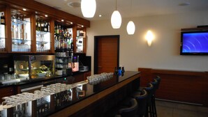 A bar area with a counter, bar stools, and a TV mounted on the wall. - Best Western Hotel Bamberg (Bamberg)