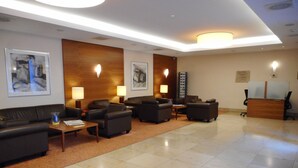 Un hall de hotel con mostrador de recepción, varias zonas de estar y obras de arte en las paredes.