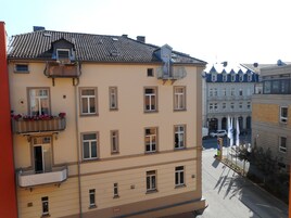 A multi-story building with a flat facade, multiple windows, and a balcony with flower boxes.
