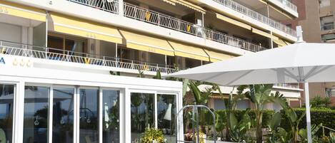 Una terraza en la azotea con mobiliario azul para exteriores, una mesa blanca y vistas a un edificio de varios pisos con balcones.