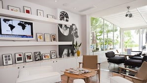 Un hall d’hôtel moderne doté d’un grand téléviseur mural, d’œuvres d’art encadrées, de sièges confortables et de grandes fenêtres offrant une vue sur l’extérieur.