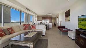 A spacious living room with a sofa, coffee table, and television. - Space Holiday Apartments (Maroochydore)