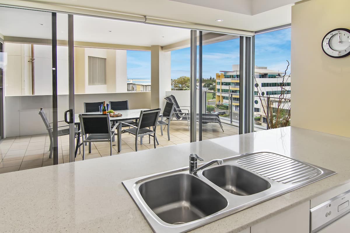 A modern kitchen with a large window, a dining area with chairs, and a view of the cityscape.