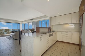 Una cocina moderna con una isla grande, muebles blancos y vistas al exterior.