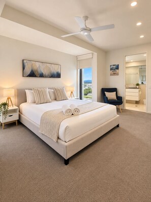 A modern bedroom with a large bed, a ceiling fan, and a view through a window. - Space Holiday Apartments (Maroochydore)