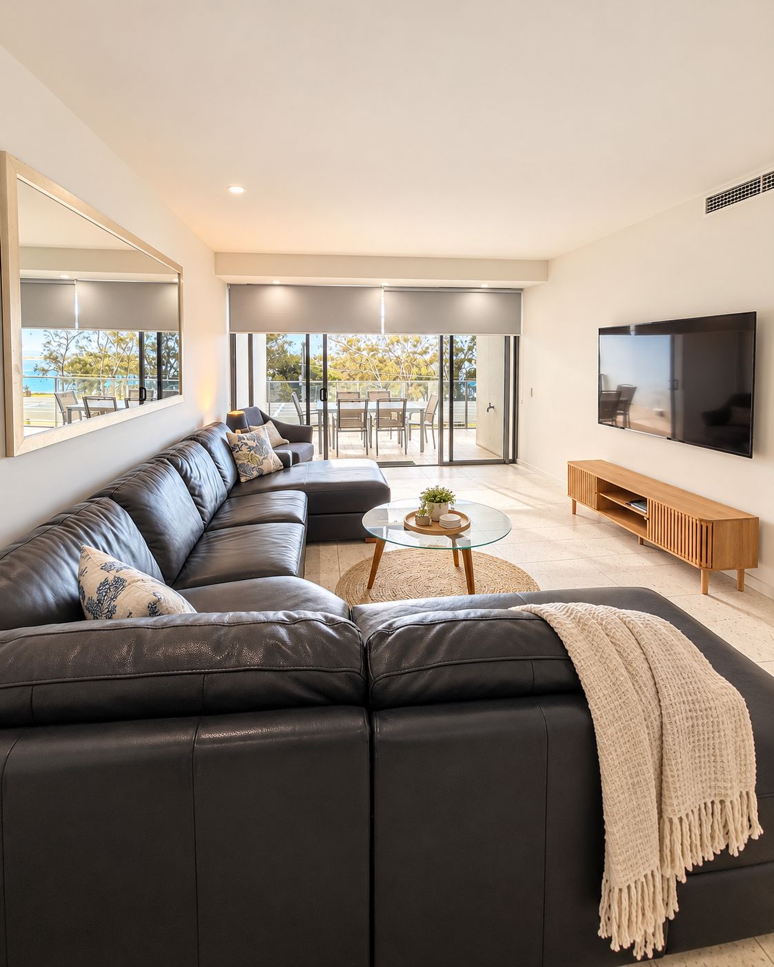 A modern living room with a sectional sofa, a coffee table, and a TV mounted on the wall.