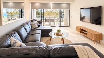 A modern living room with a sectional sofa, a coffee table, and a TV mounted on the wall.