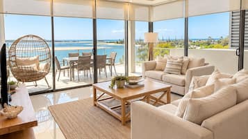 A spacious living room with a large window, a sofa, a coffee table, and a hanging chair.