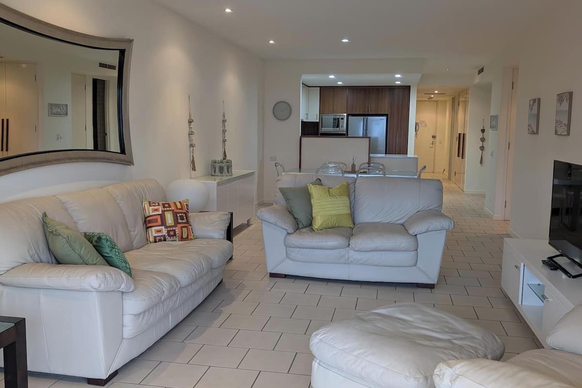 A modern living room with two sofas, a coffee table, and a TV stand.