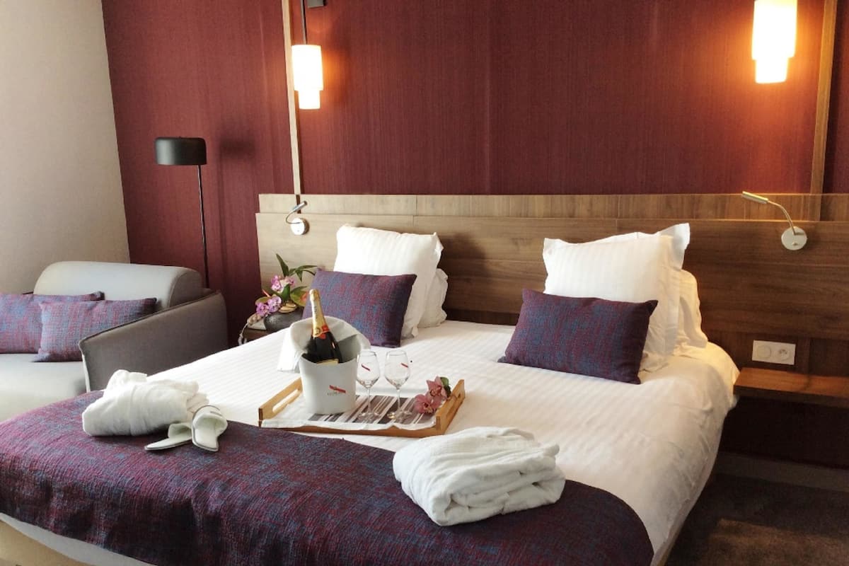 A hotel room with a large bed, two bedside tables, a nightstand, a chair, and a lamp.
