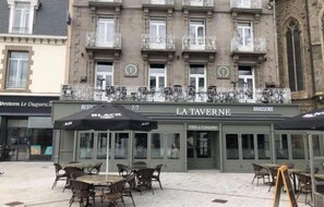 A building with a sign for 'LA TAVERNE BRASSERIE' and outdoor seating with tables and chairs. - Best Western Le Duguesclin (Saint-Brieuc)