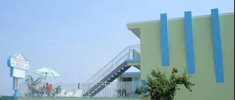 A building with a green and blue facade, a covered parking area, and a sign indicating a motel.