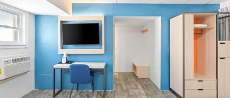 A room with a desk, chair, and a wardrobe.