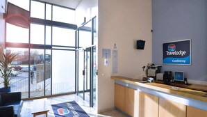 Un área de recepción con un mostrador de madera, una computadora y un cartel de Travelodge Castle Troy.