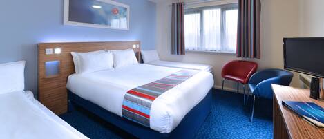 A hotel room with a large bed, a desk with a computer, a chair, and a television.