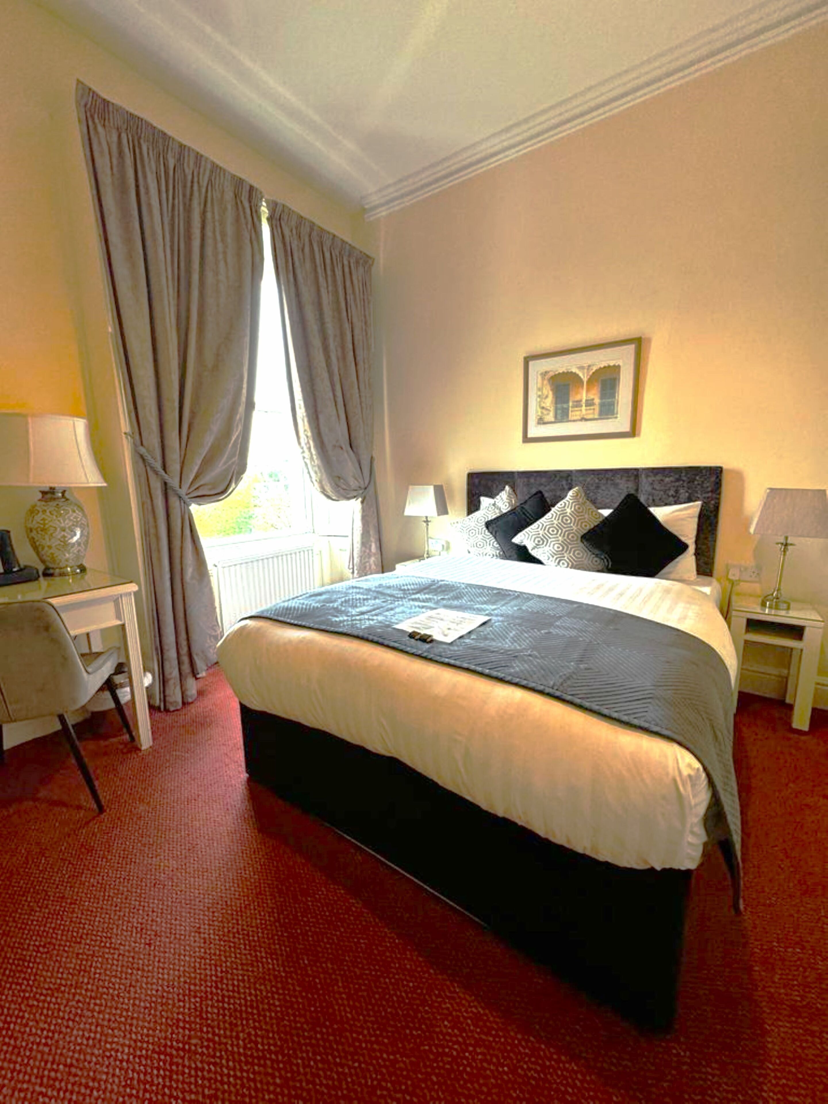 A neatly arranged hotel room with a large bed, a desk, and a chair.