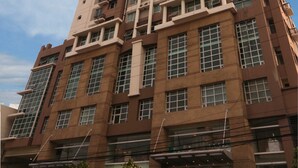 A high-rise building with multiple floors, large windows, and a modern architectural design. - Lancaster Hotel Manila (Mandaluyong)