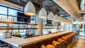 A bar area with multiple seating options, a long counter with various bottles, and a television screen.