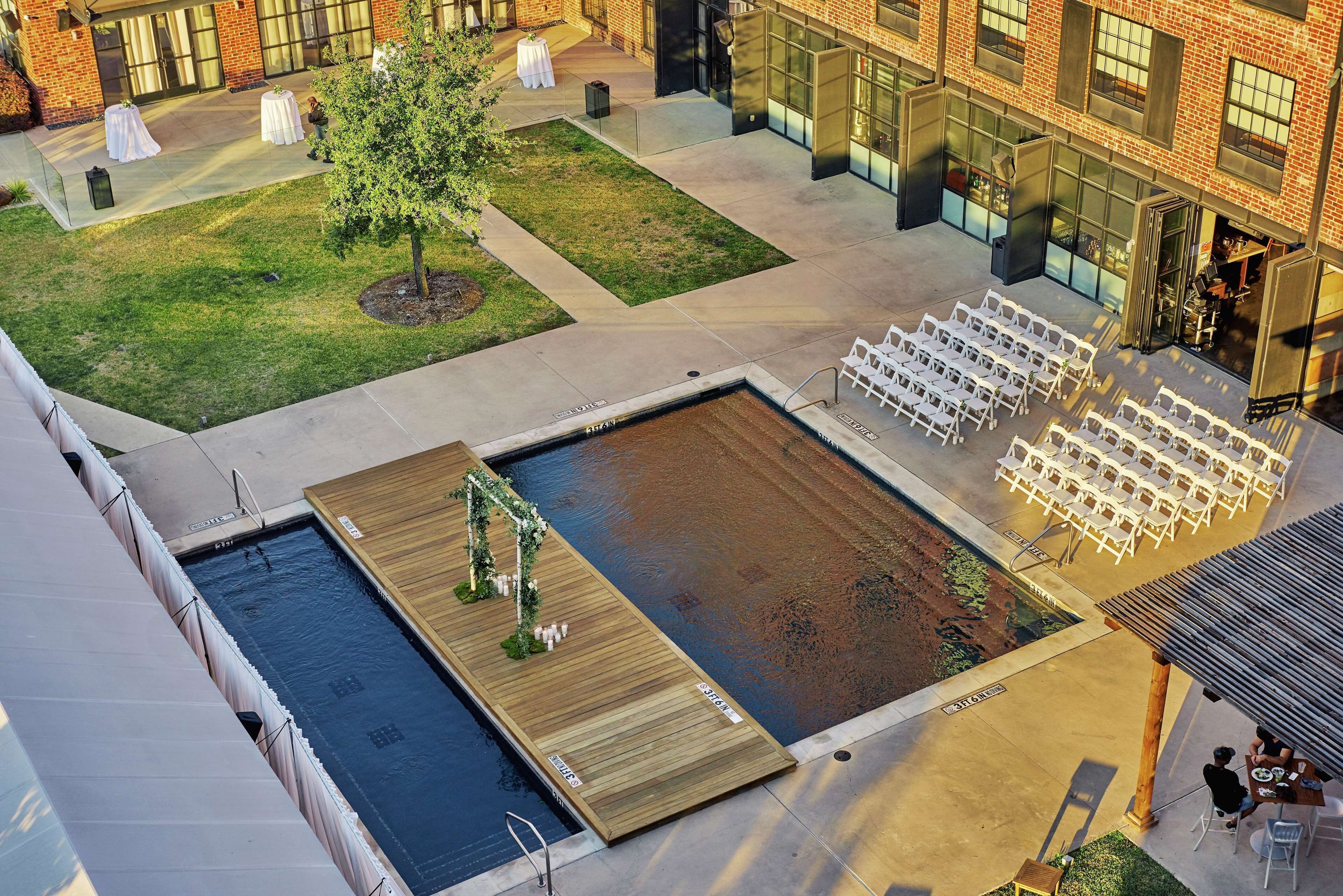 Un área de piscina en la azotea con terraza de madera, asientos y un pequeño jardín.