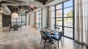 A spacious room with large windows, a table with chairs, and an exit sign.