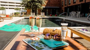 A poolside area with lounge chairs, a magazine, a bottle of sunscreen, and a wicker basket.