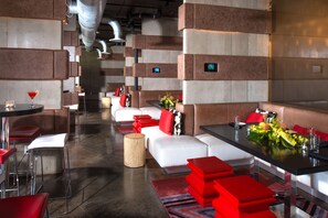 Ein modernes Restaurant mit weißer und roter Sitzmöbel, einer Bar und einer langen Theke mit floraler Dekoration.
