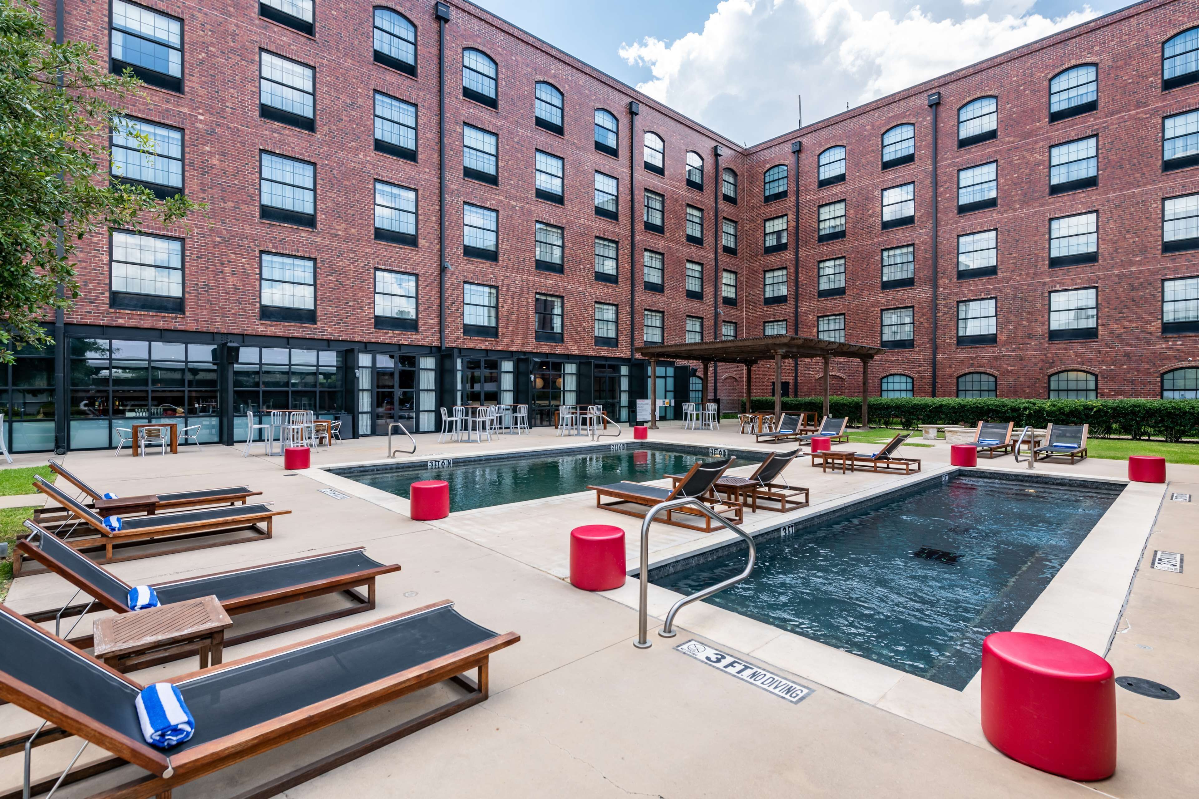 A pool area with lounge chairs and a red cylindrical object.