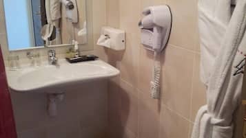 A bathroom with a sink, a mirror, a hairdryer, a towel rack, and a trash can.