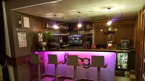 A bar area with a checkered floor, bar stools, and a counter with a neon sign.