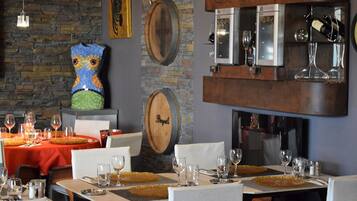L’intérieur d’un restaurant est décoré de barils en bois, d’une œuvre d’art en mosaïque représentant une chouette, et comprend un espace bar avec des verres et des bouteilles.