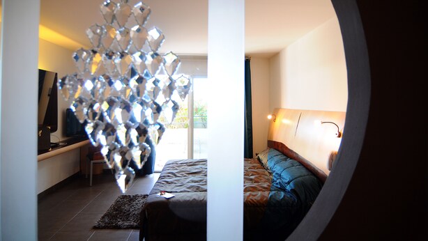 A bedroom with a bed, a desk, a chair, and a decorative crystal sculpture.