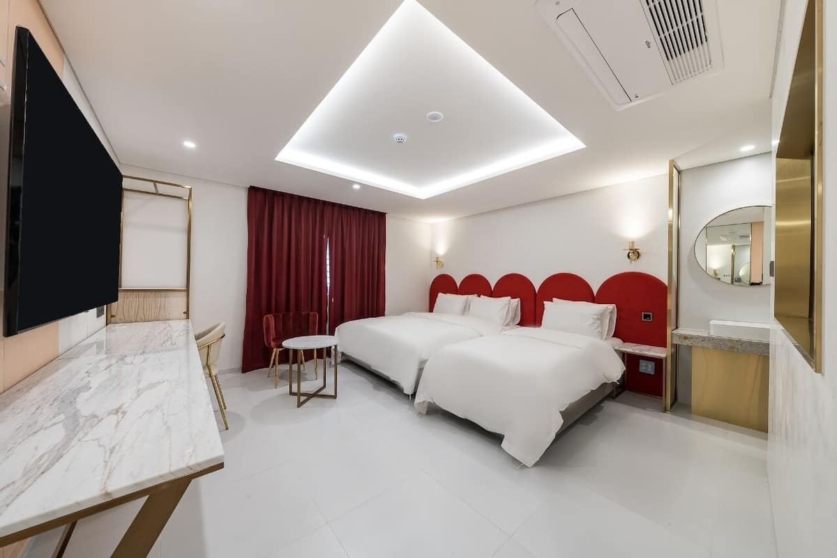 A hotel room with a large bed, a desk, and a TV.