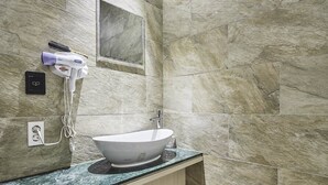 Une salle de bain avec un lavabo blanc, des murs en marbre et un sèche-cheveux fixé au mur.