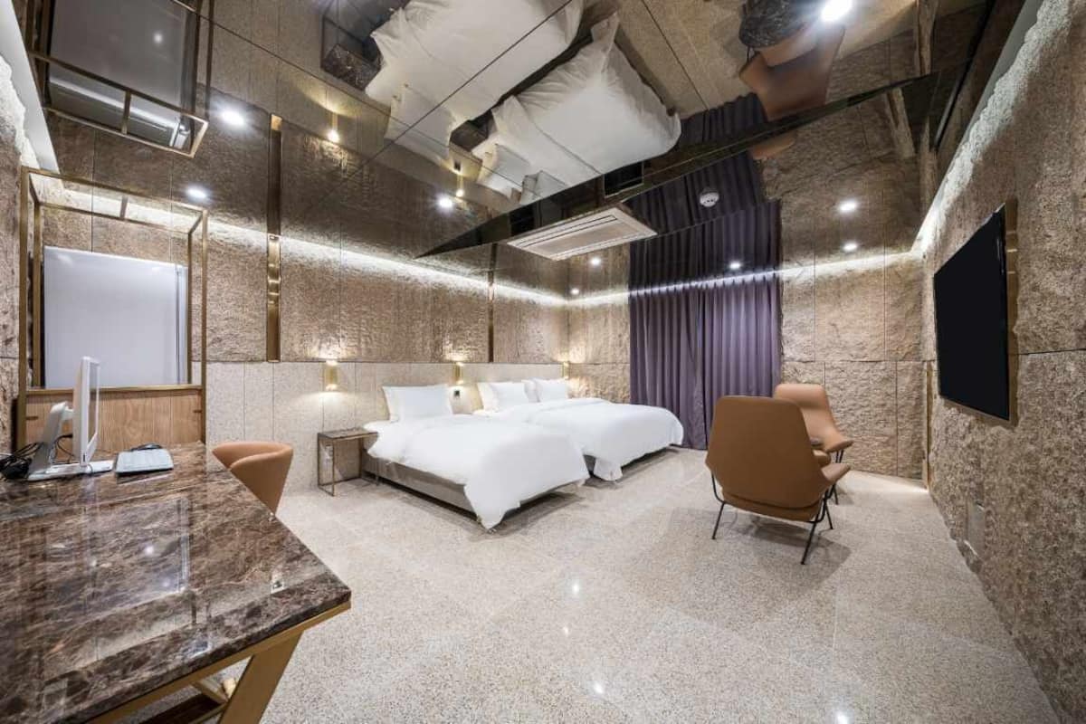 A modern hotel room with a large bed, a desk, and a TV.