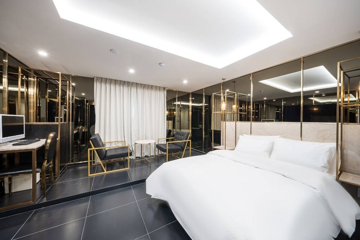 A modern hotel room with a large bed, a desk, and a seating area.