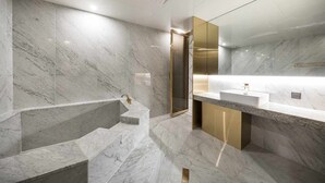 Une salle de bain moderne avec des murs en marbre, une baignoire sur pieds et un grand miroir.