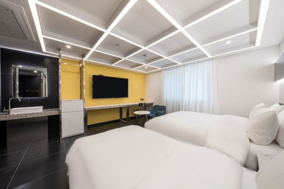 Une chambre d’hôtel moderne dotée d’un grand lit, d’un bureau, d’une télévision à écran plat et d’une salle de bain avec un lavabo et un miroir.