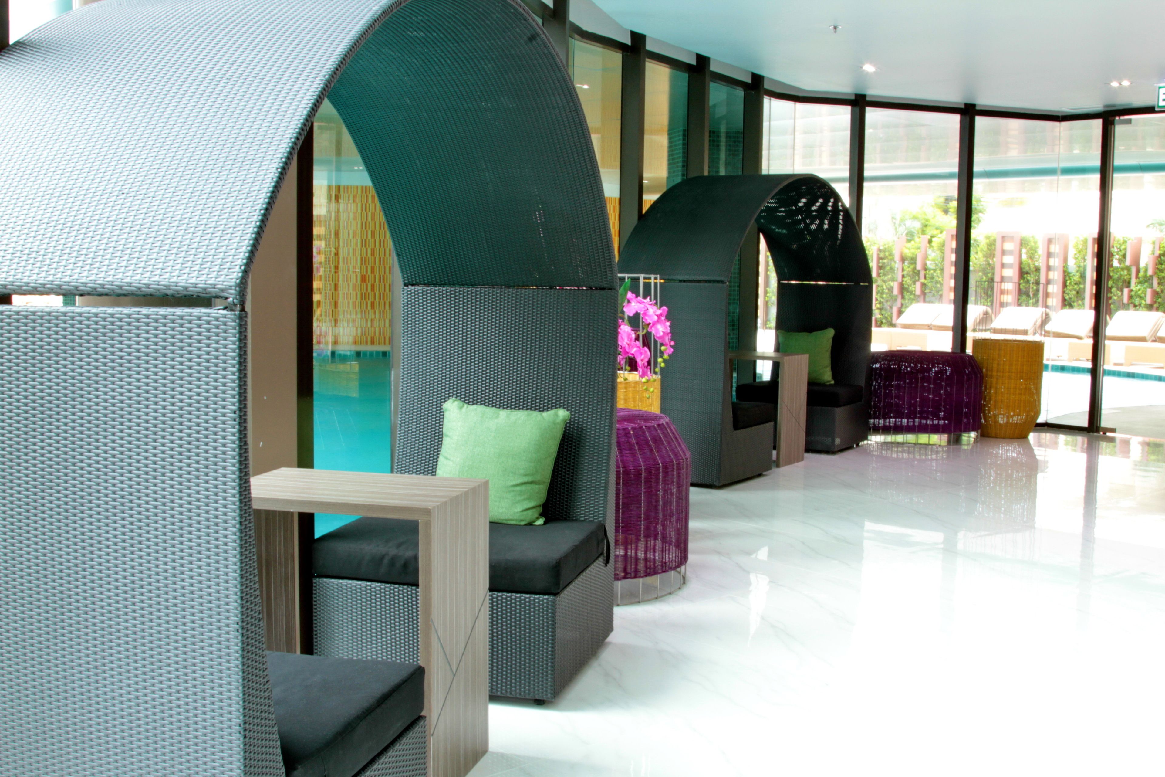 A modern lounge area with curved seating and a glass wall offering a view of the outdoors.