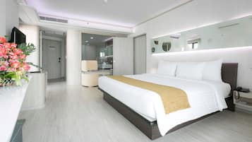 A modern hotel room with a large bed, a bedside table, a mirror, and a bathroom visible through an open door.