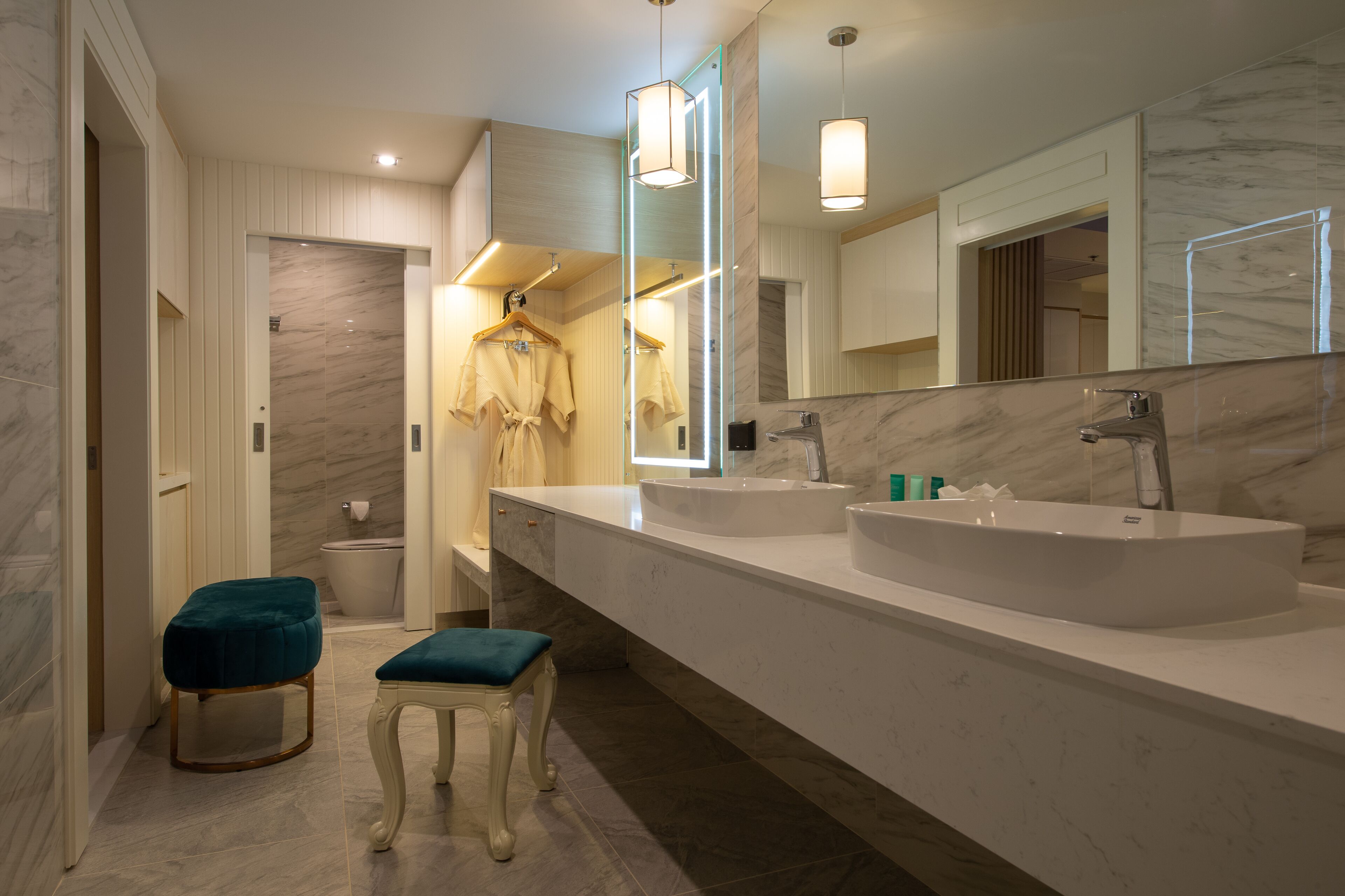 A modern bathroom with two sinks, a large mirror, and a robe hanging on a rack.